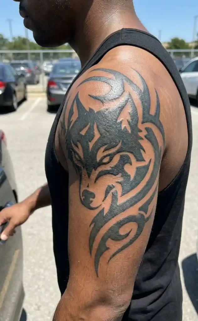 bold tribal wolf tattoo on a man’s deltoid and upper arm