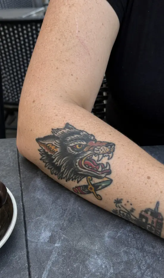 A traditional wolf and dagger tattoo on the outer forearm. Of all the styles, old-school suits this placement best, because bold lines fight off the sun the forearm constantly catches.
